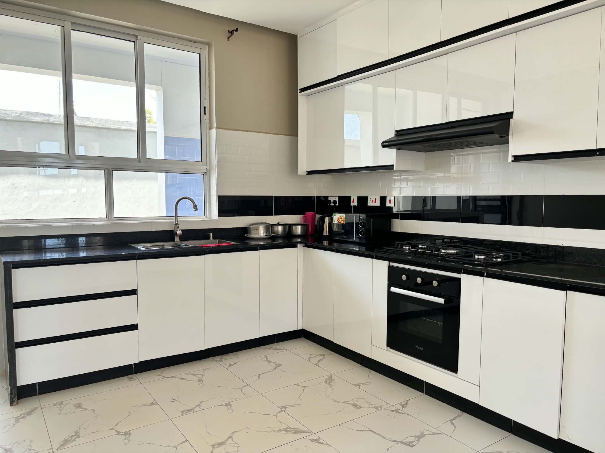 Open-plan kitchen with dark granite surfaces and white cabinetry